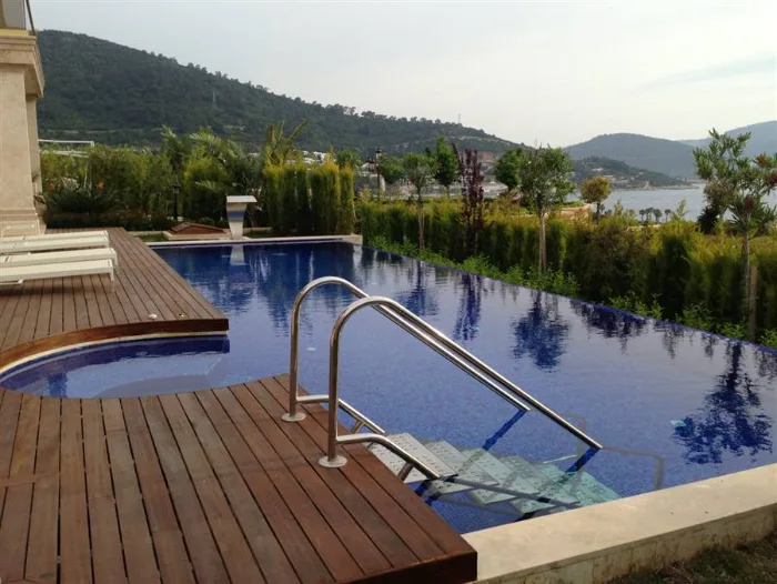 Stainless steel pool ladder on a sea-view deck-level pool, descending from the timber deck