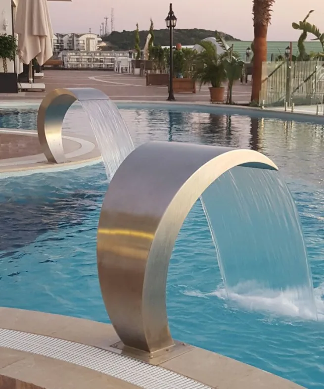 Stainless steel cobra type waterfall in operation at a hotel pool